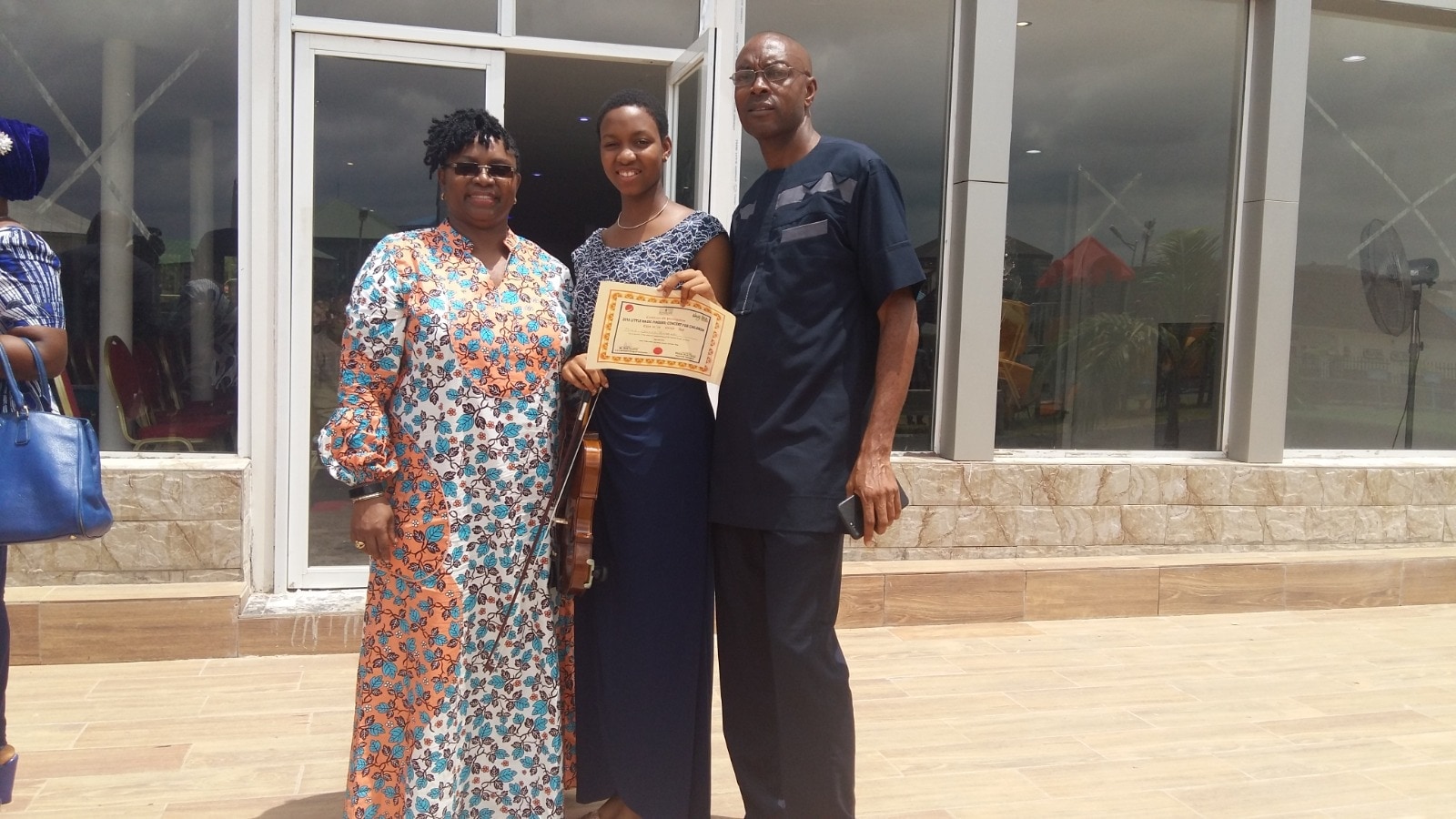 Dr. Oby Nwokedi outside a building with two others, one holding a framed certificate