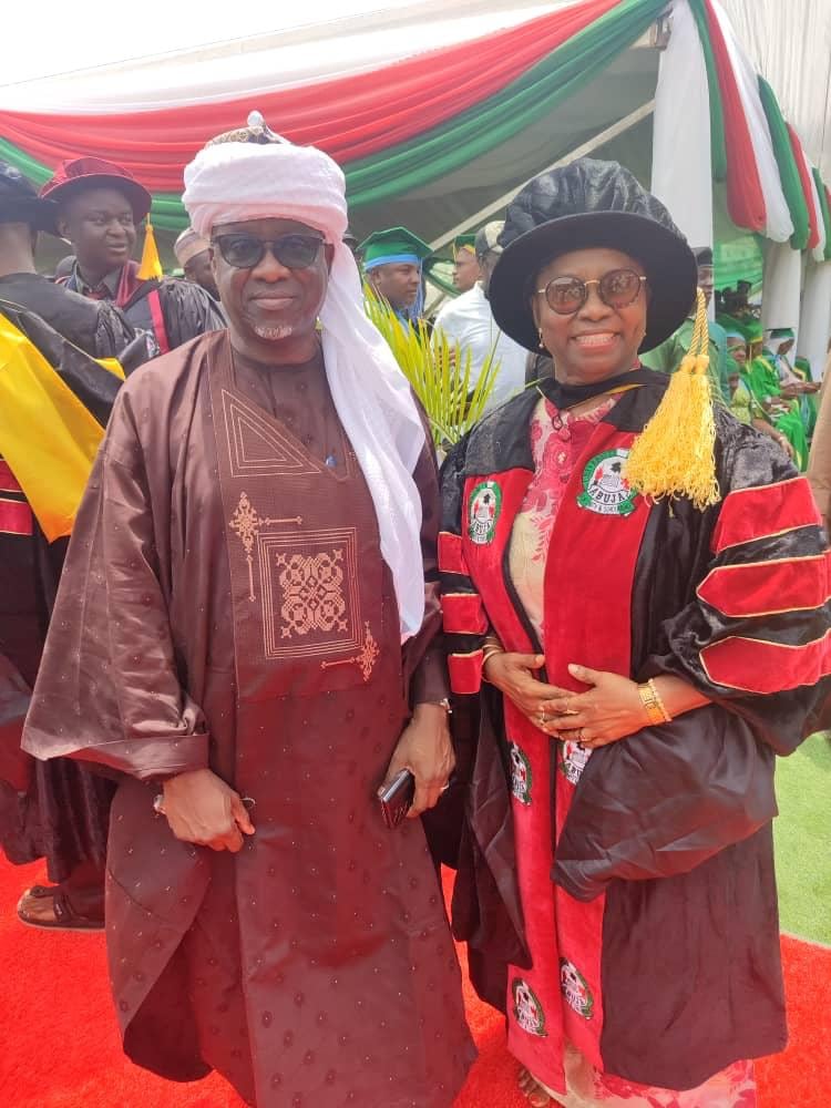 Dr. Oby Nwokedi in doctoral robes on a red carpet at convocation, beside a companion in traditional dress