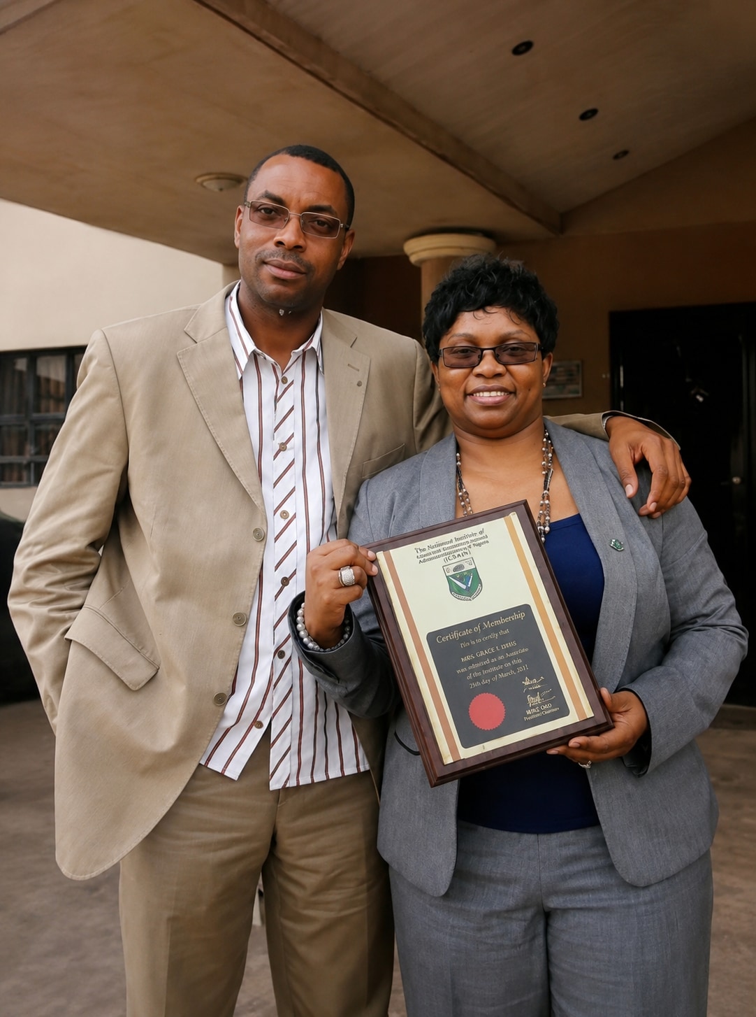 Dr. Oby Nwokedi holding a framed award, her husband beside her
