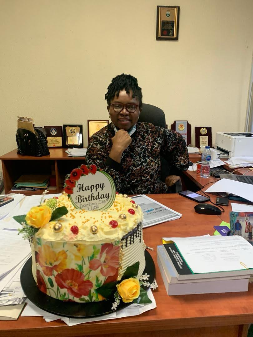 Dr. Oby Nwokedi behind her desk on her birthday, papers stacked beside her