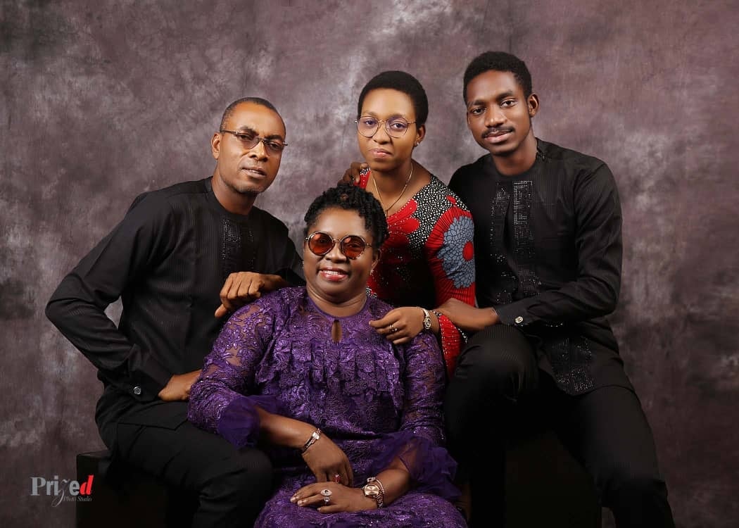 A studio portrait of Dr. Oby Nwokedi seated in purple with her family around her