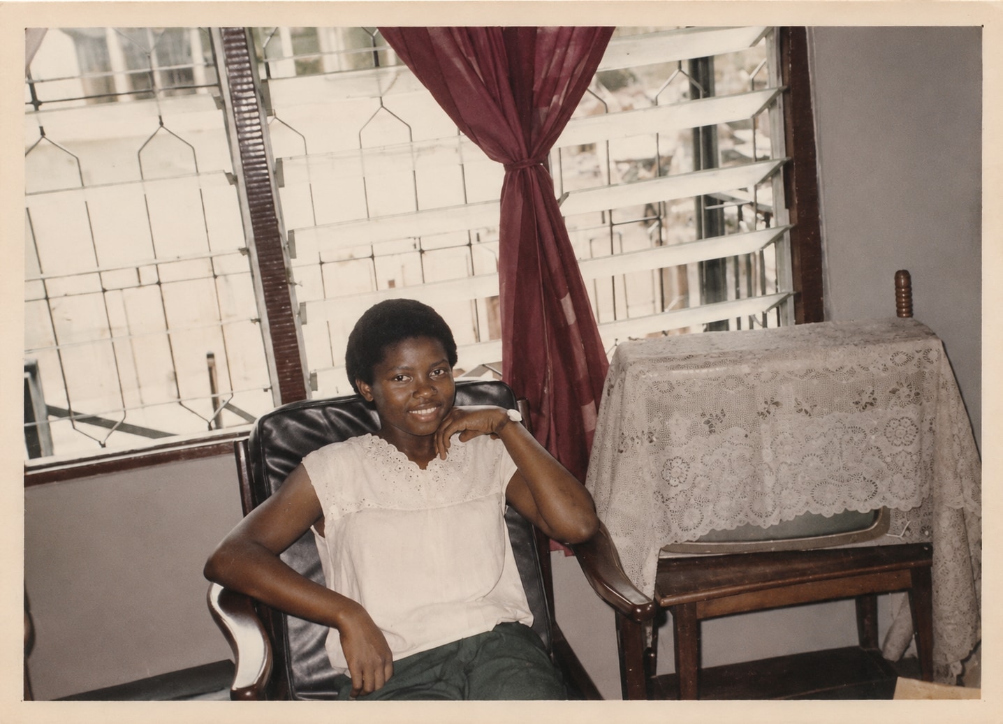 Oby reclining in an armchair at home beside a curtained window