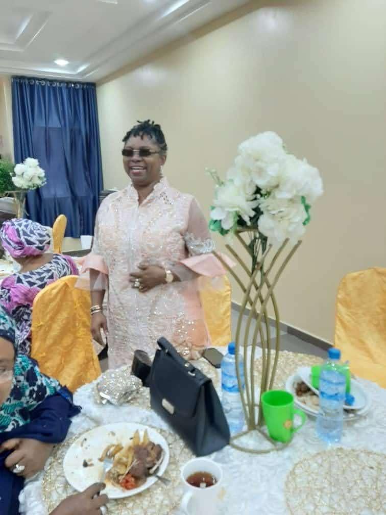 Dr. Oby Nwokedi standing at a dinner table in peach lace, laughing