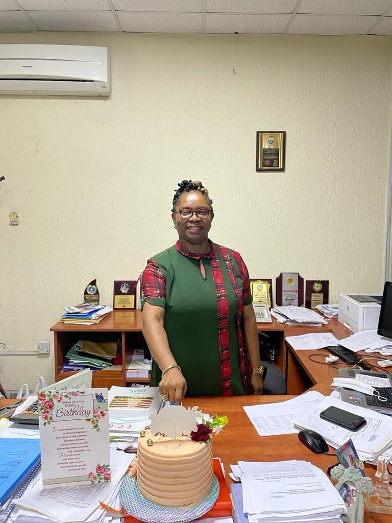 Dr. Oby Nwokedi at her desk with a celebration cake