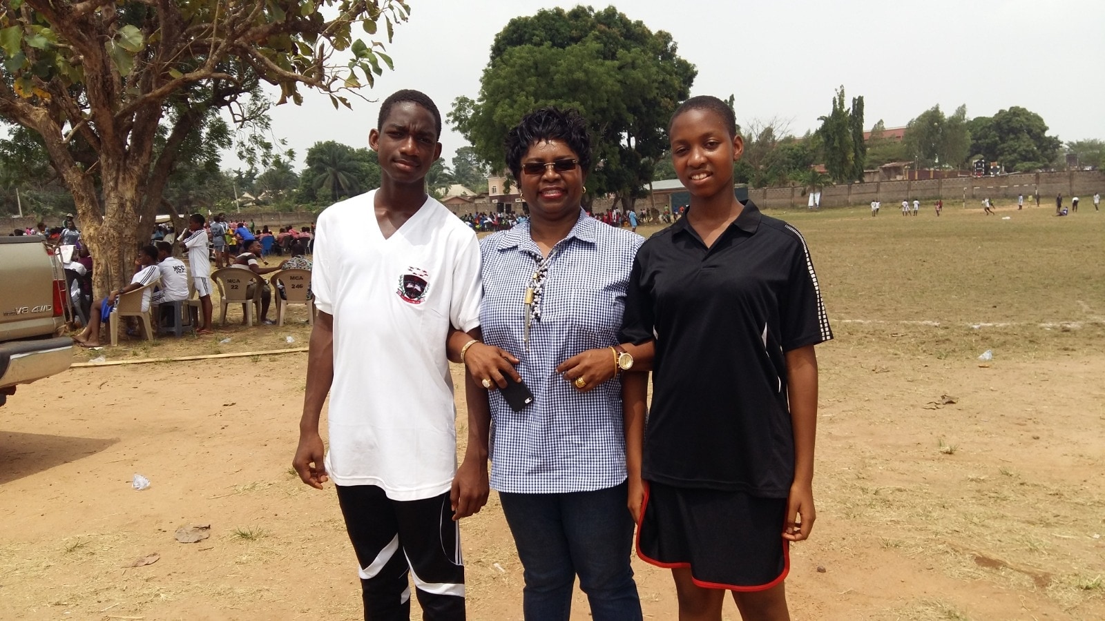 Dr. Oby Nwokedi standing between her son and daughter on a school sports field