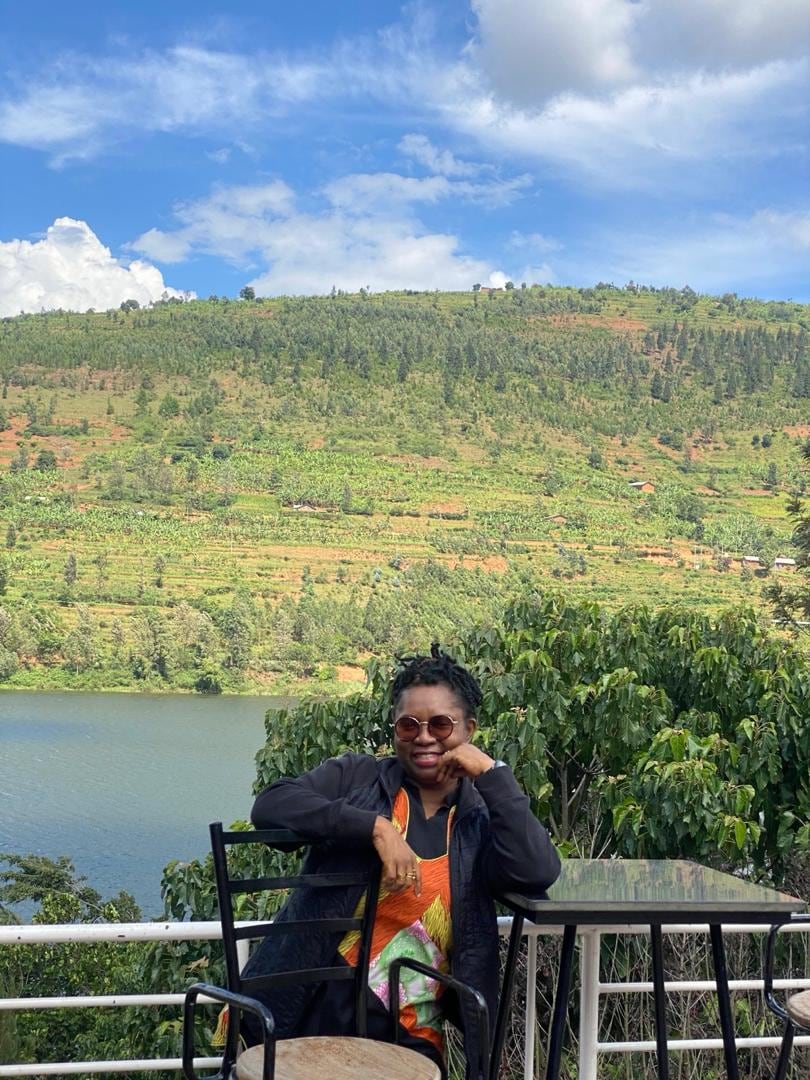 Dr. Oby Nwokedi seated at a terrace table high above a lake and terraced hillside